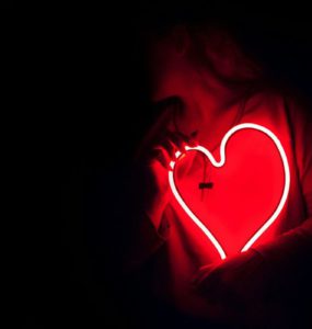 a heart shaped neon sign in the dark