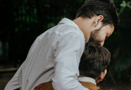 A heartfelt moment between father and son sharing a tender embrace outdoors.