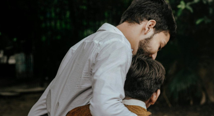 A heartfelt moment between father and son sharing a tender embrace outdoors.