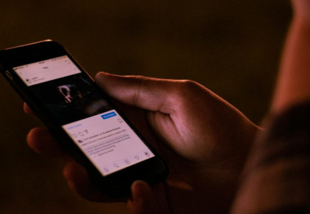 A person interacts with a smartphone in a dimly lit setting, emphasizing mobile technology usage.