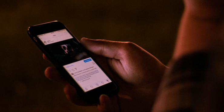 A person interacts with a smartphone in a dimly lit setting, emphasizing mobile technology usage.