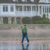 Serene scene of a man fishing in front of a grand lakeside mansion.