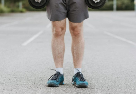Crop unrecognizable male training with heavy dumbbells becoming stronger while working on body