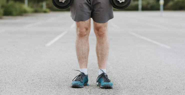 Crop unrecognizable male training with heavy dumbbells becoming stronger while working on body