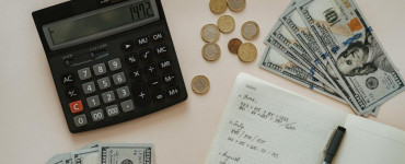 Flat lay of calculator, cash, coins, and handwritten notes for budget planning.