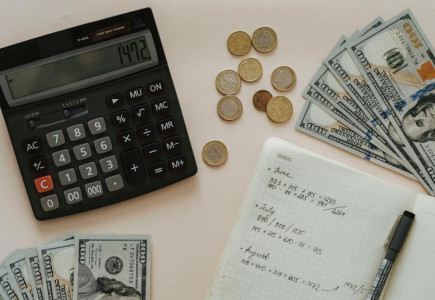 Flat lay of calculator, cash, coins, and handwritten notes for budget planning.