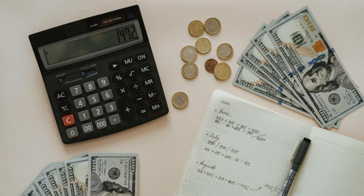 Flat lay of calculator, cash, coins, and handwritten notes for budget planning.