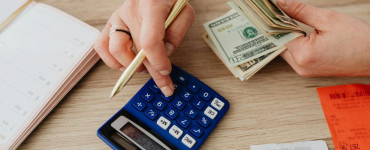 Hands handling cash and calculator for budget planning. Modern financial scene.