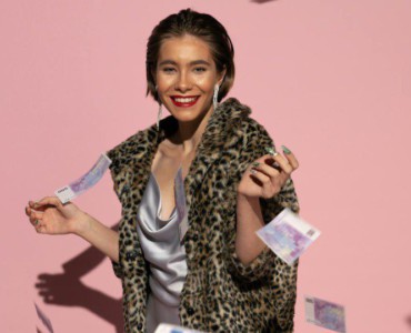 Stylish woman in fur coat with flying euro notes and pink background. Bright, fashionable, and confident.