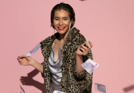 Stylish woman in fur coat with flying euro notes and pink background. Bright, fashionable, and confident.