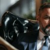 Stylish businessman with a beard reading a newspaper indoors.