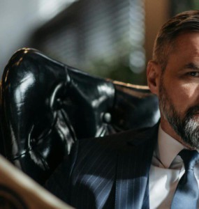 Stylish businessman with a beard reading a newspaper indoors.
