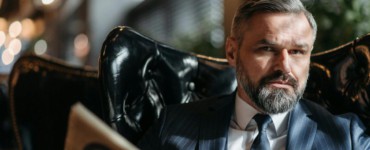 Stylish businessman with a beard reading a newspaper indoors.