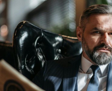 Stylish businessman with a beard reading a newspaper indoors.