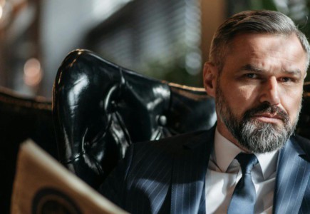 Stylish businessman with a beard reading a newspaper indoors.