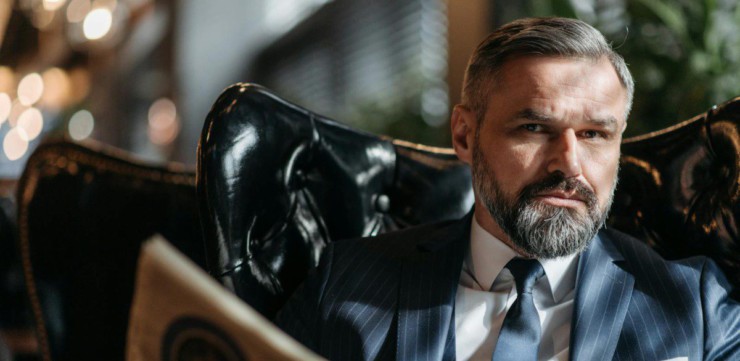 Stylish businessman with a beard reading a newspaper indoors.