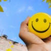 a hand holding a yellow smiley face ball