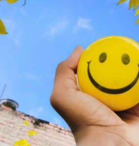 a hand holding a yellow smiley face ball