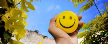 a hand holding a yellow smiley face ball