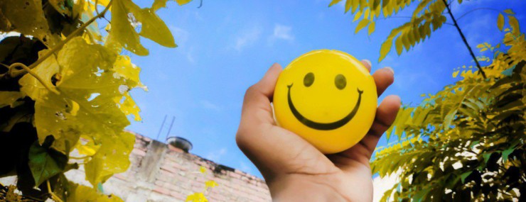 a hand holding a yellow smiley face ball