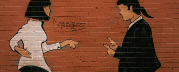 Two figures painted on a brick wall arguing.