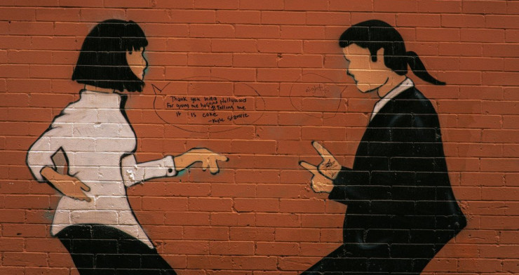 Two figures painted on a brick wall arguing.