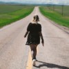 a woman walking down the middle of a road