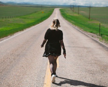a woman walking down the middle of a road
