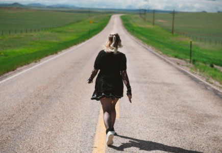 a woman walking down the middle of a road