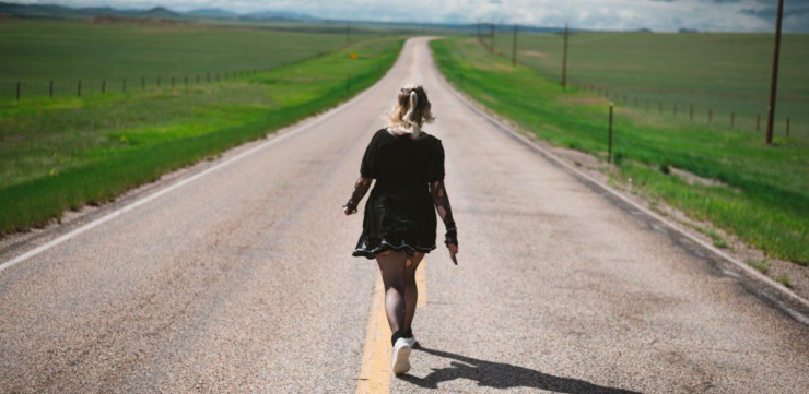 a woman walking down the middle of a road