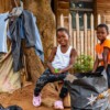 Two smiling children in front of a wooden house.
