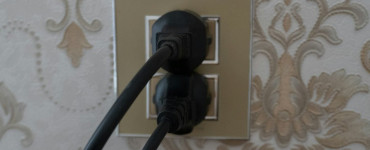 Two black plugs inserted into a gold electrical outlet.