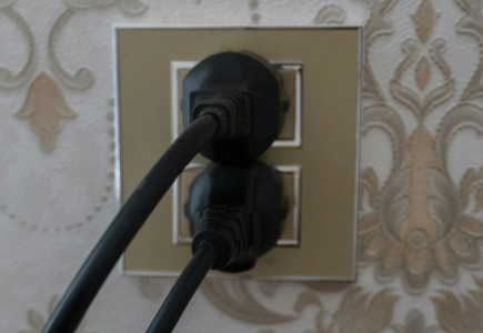 Two black plugs inserted into a gold electrical outlet.