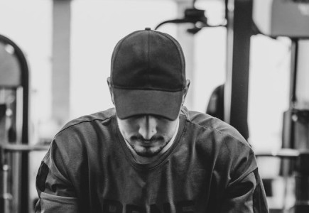 man in black jacket and knit cap sitting on bench
