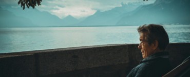 man sitting while holding a book watching on body of water