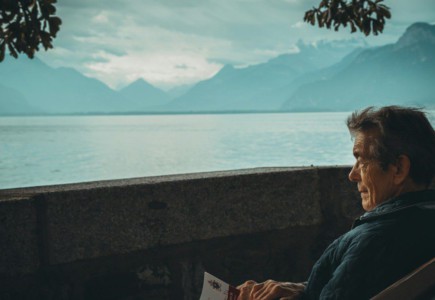 man sitting while holding a book watching on body of water