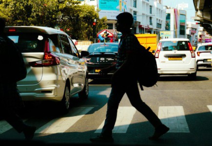 People crossing a busy city street with cars.