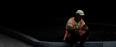 man in white shirt playing guitar sitting on concrete pavement