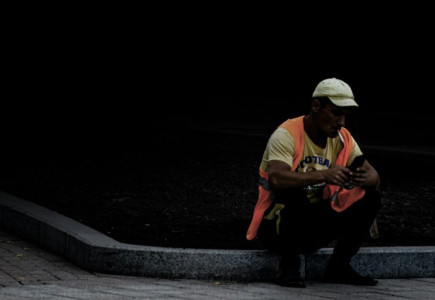 man in white shirt playing guitar sitting on concrete pavement