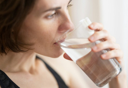 woman in black tank top drinking water