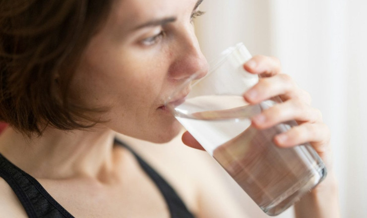 woman in black tank top drinking water
