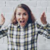 Woman with hands raised shouting in frustration.