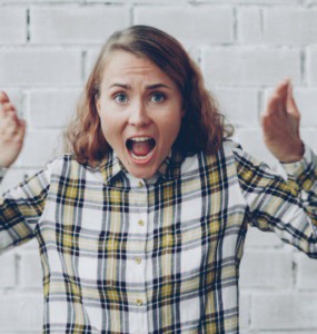 Woman with hands raised shouting in frustration.