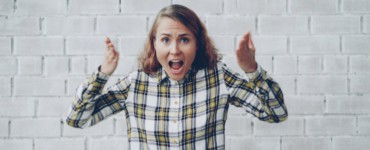 Woman with hands raised shouting in frustration.