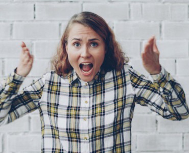 Woman with hands raised shouting in frustration.