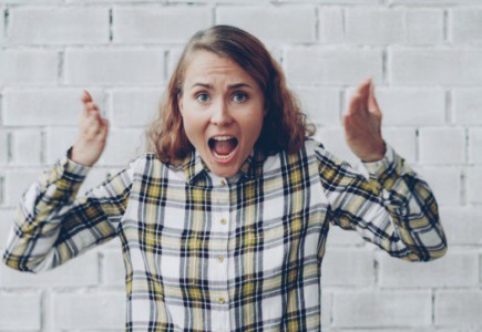 Woman with hands raised shouting in frustration.