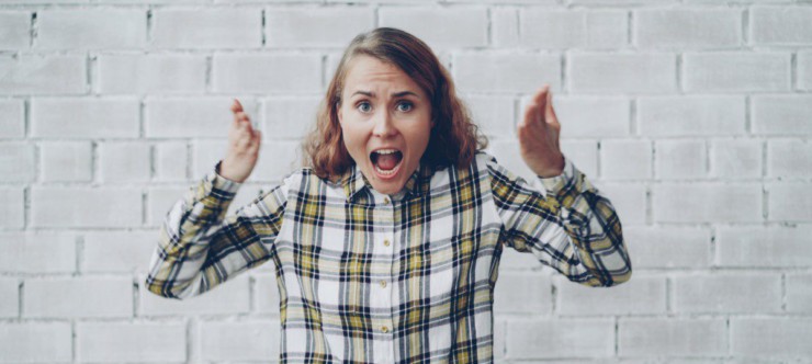 Woman with hands raised shouting in frustration.