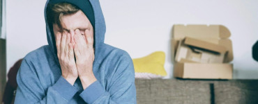 man covering face with both hands while sitting on bench
