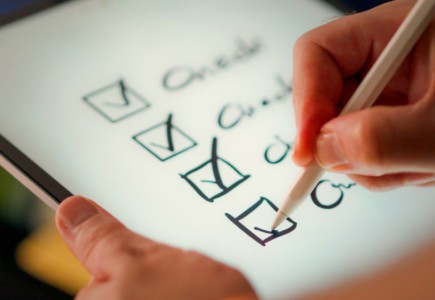 A hand marks off items on a checklist.